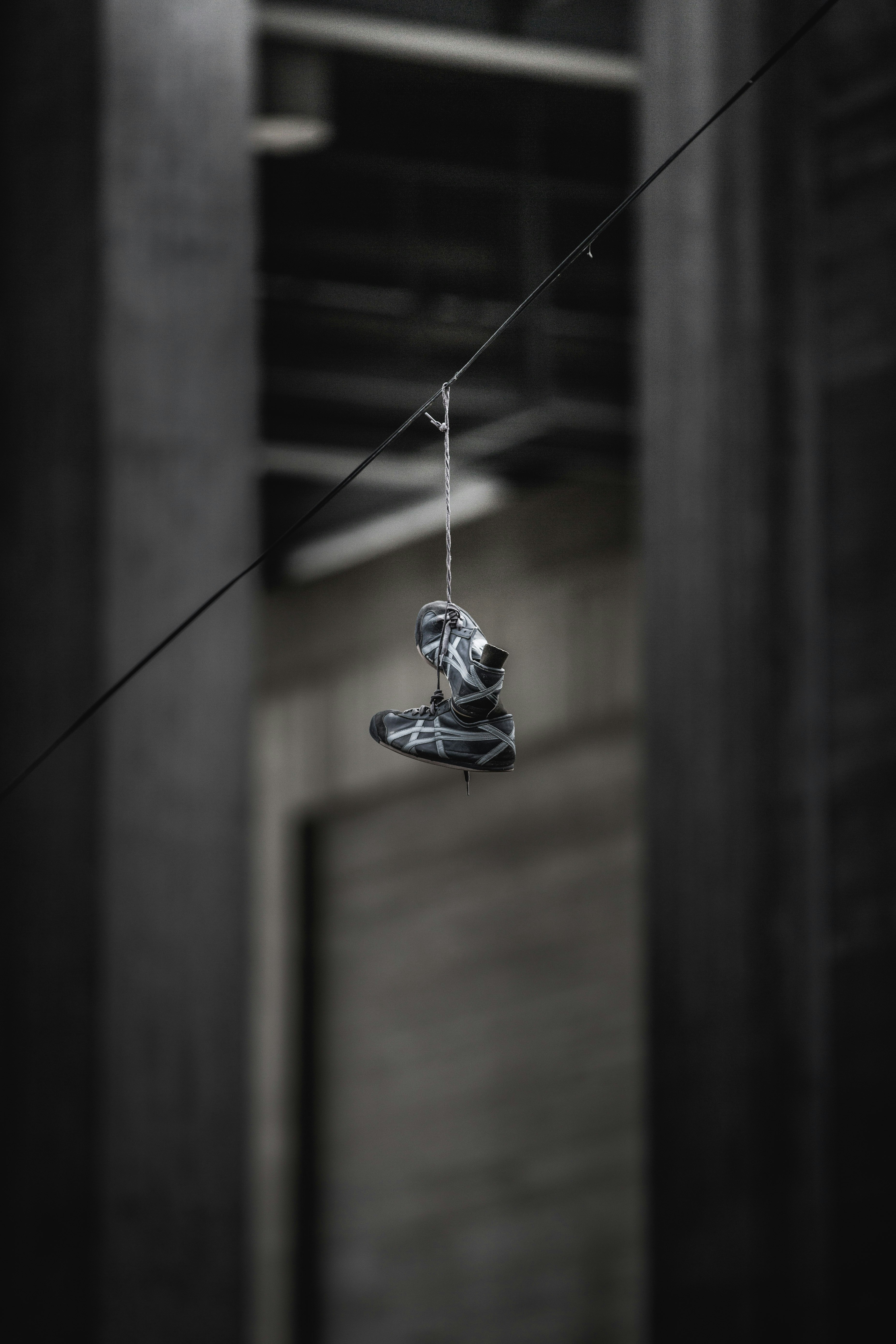 pair of black-and-gray ASICS shoes hanging on wire